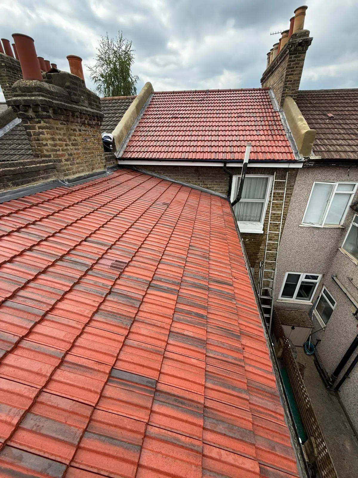 Completed red interlocking tile roof with repointed brick chimney stacks