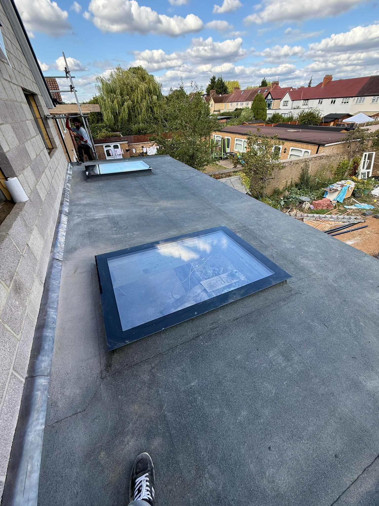 Flat roof extension with two glass skylights and a new grey mineral-finish covering