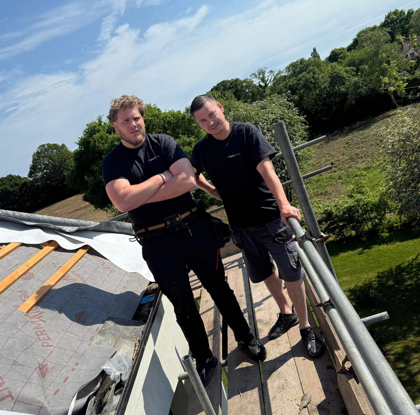 Two Adrent Roofing roofers in branded black t-shirts standing on site