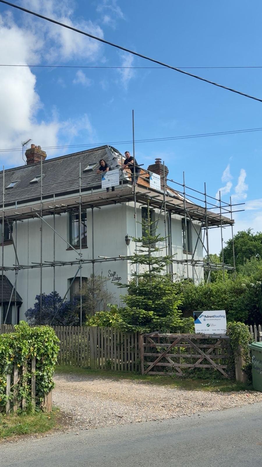 House with Adrent Roofing scaffolding banners and a branded sign at the front