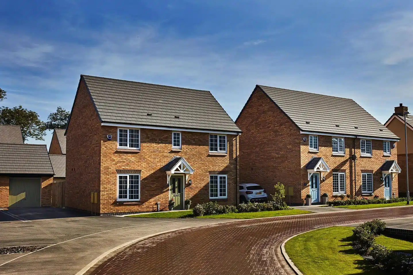 Terrace of new brick homes with steeply pitched dark grey tiled roofs